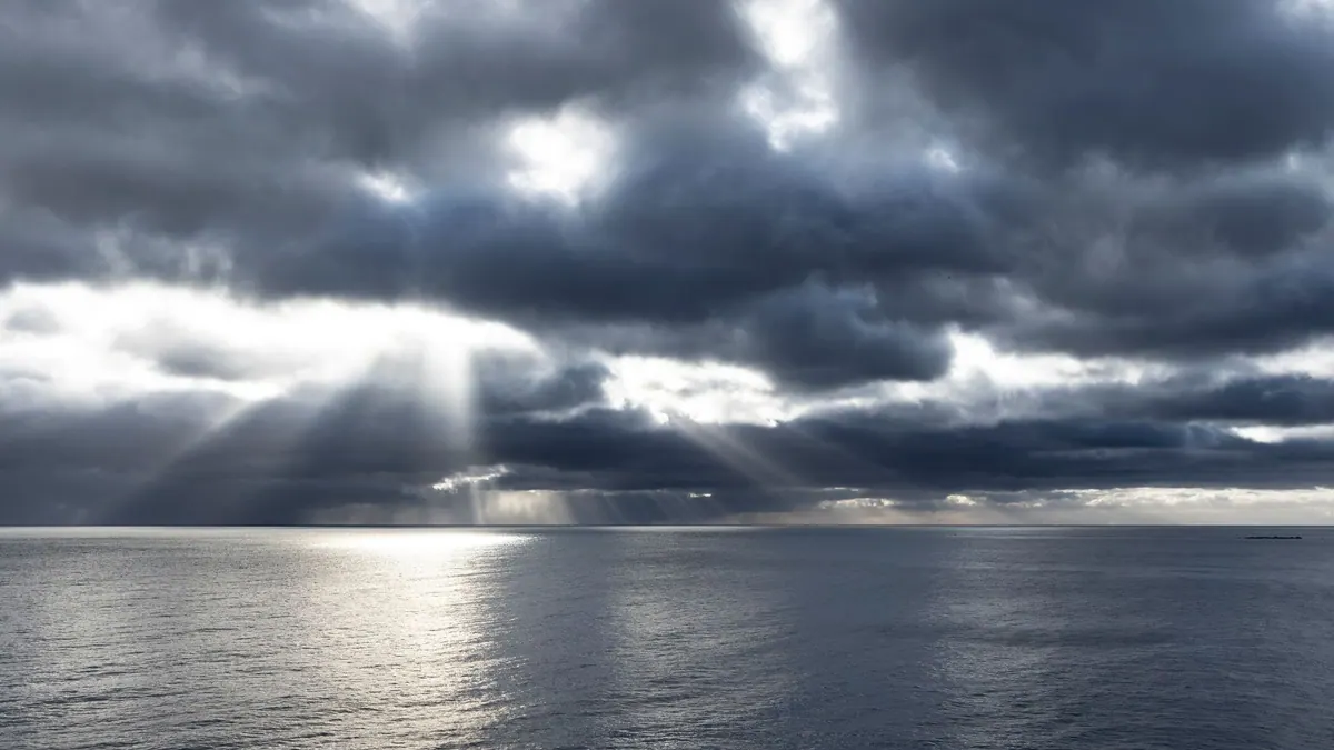 Sunbeams breaking through storm clouds over the open sea