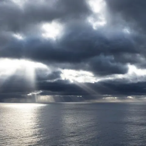 Sunbeams breaking through storm clouds over the open sea