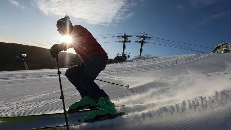 Skier carving a groomed run in low winter sun