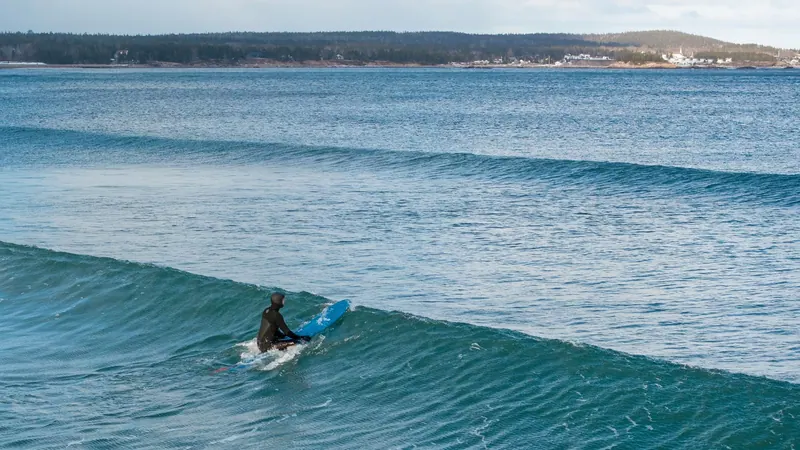 Surfer paddling into a turquoise wave