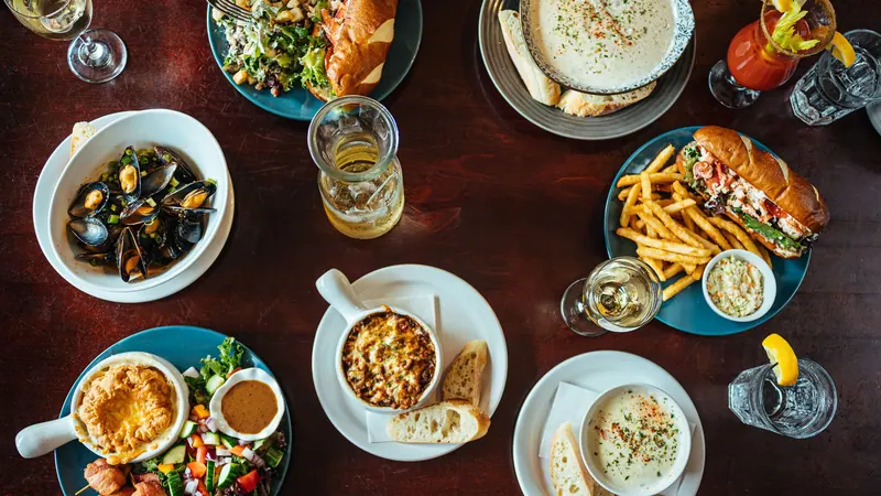 Table of seafood dishes, fries and drinks seen from above