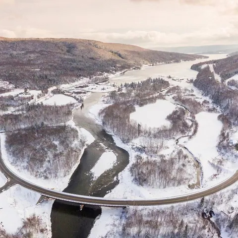 Aerial view of the Cabot Trail curving across a bridge through a snowy river valley