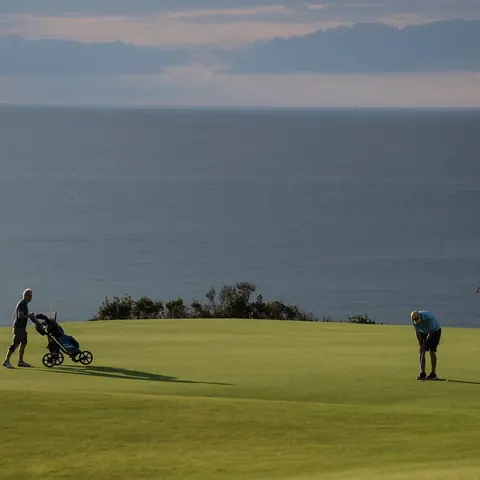 Golfers on a green above the ocean