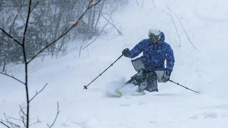 Skier in a blue jacket turning through fresh powder