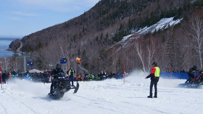 Snowmobile racing below a snowy mountainside