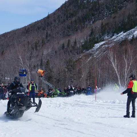 Snowmobile racing below a snowy mountainside