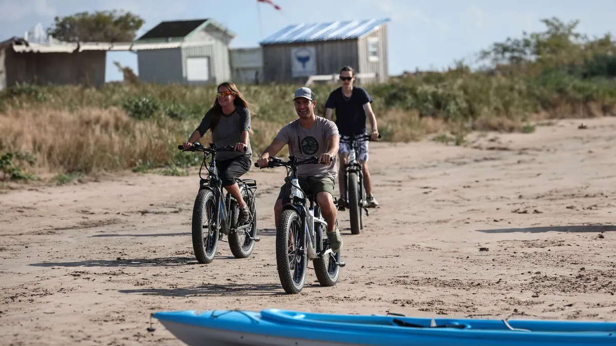 Three riders on fat-tire e-bikes on a sandy beach