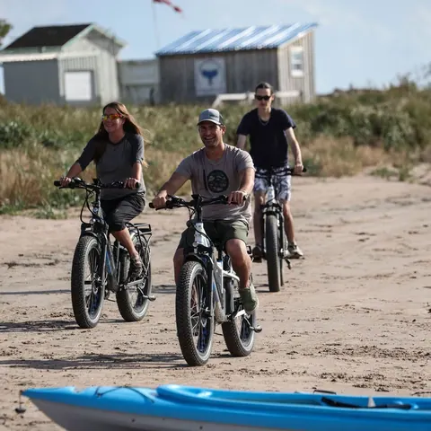 Three riders on fat-tire e-bikes on a sandy beach