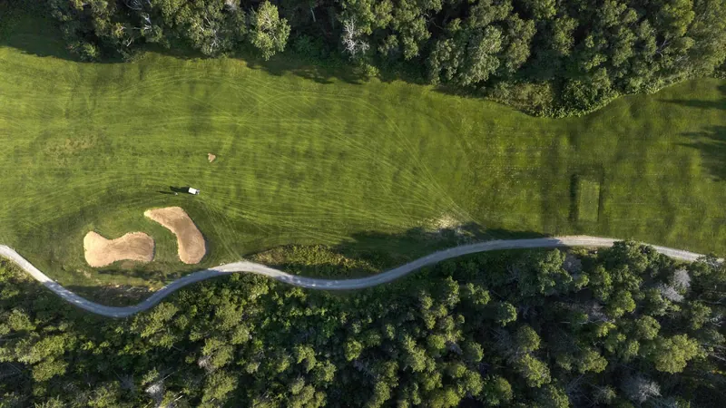 Aerial view of a fairway and bunker cut through the forest