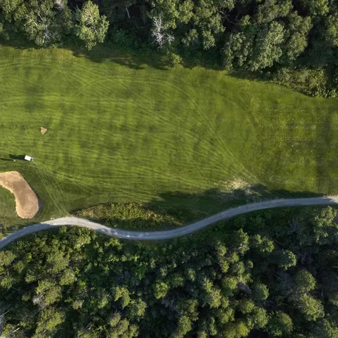 Aerial view of a fairway and bunker cut through the forest
