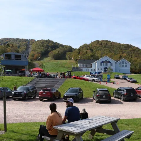 Guests relaxing at picnic tables by the Cape Smokey base lodge in summer