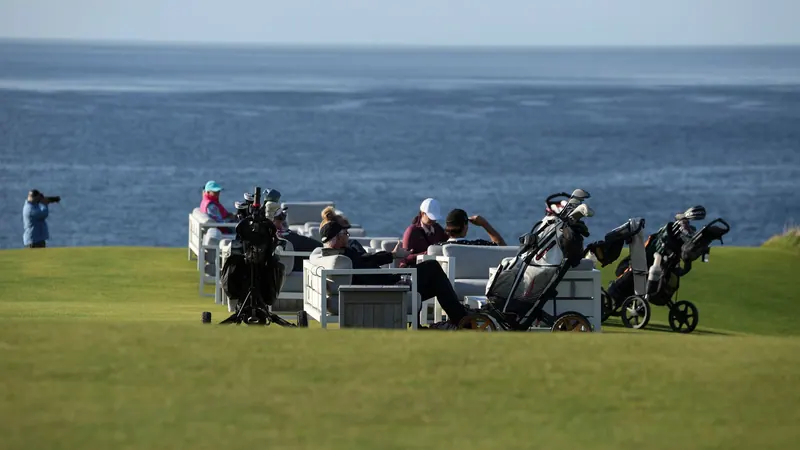 Golfers with carts gathered on a seaside course