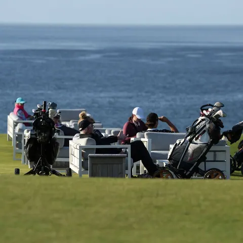 Golfers with carts gathered on a seaside course