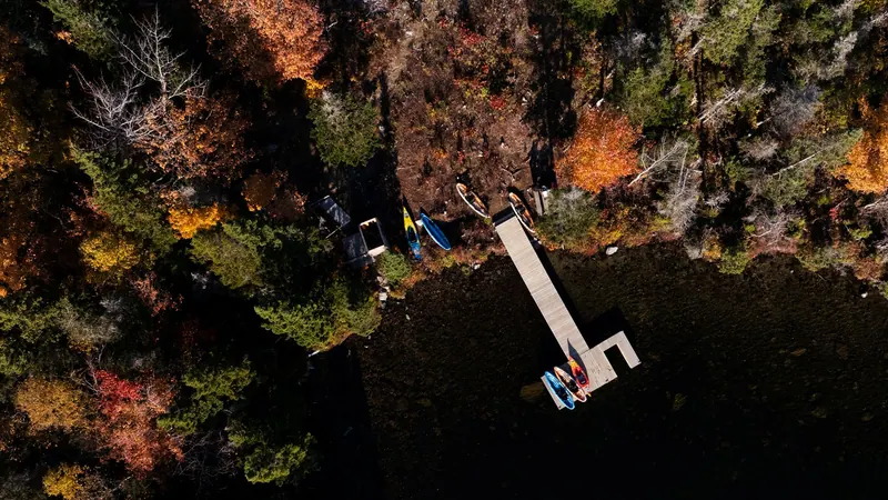 Aerial view of kayaks and a dock on an autumn lakeshore