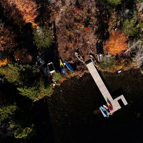 Aerial view of kayaks and a dock on an autumn lakeshore