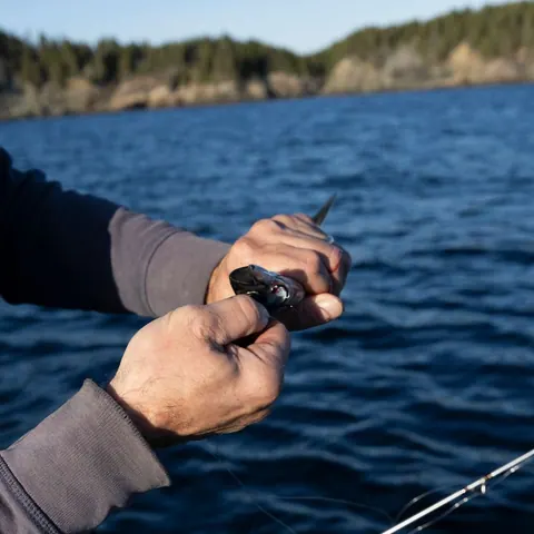 Close-up of hands reeling in a fishing line over the sea