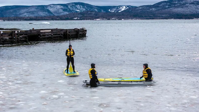Three paddleboarders in life jackets near a wharf