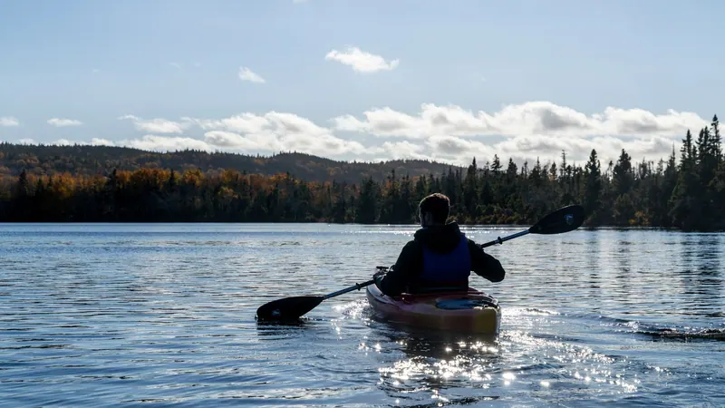 Kayaker paddling into the sun on a calm lake