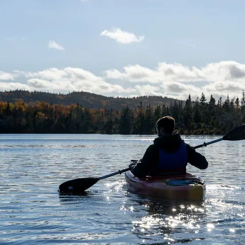 Kayaker paddling into the sun on a calm lake