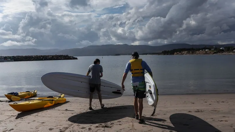 Two surfers carrying boards across the beach