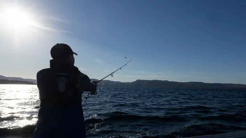 Angler casting from a boat at dusk