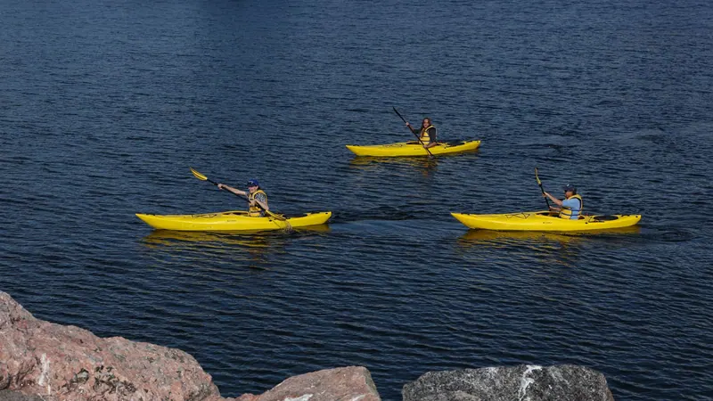 Three yellow kayaks on a calm bay
