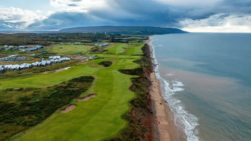 Aerial view of a golf course running beside a long beach