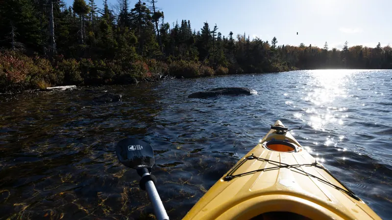 Paddler’s view from a yellow kayak on a sunlit river