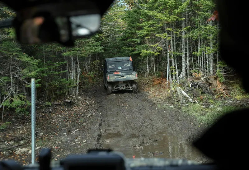 Off-road vehicle driving a muddy track through the forest
