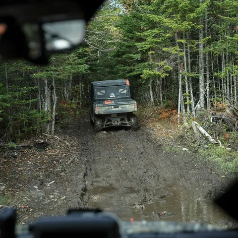 Off-road vehicle driving a muddy track through the forest