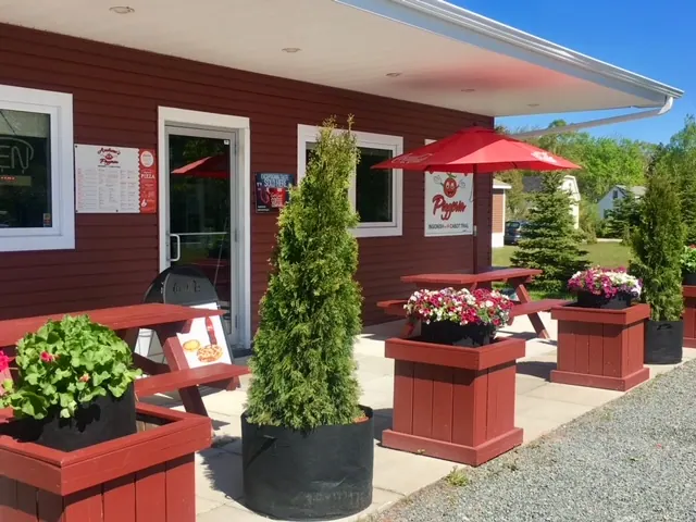 Red-painted Andrew’s Pizzeria with flower planters and picnic tables on the deck