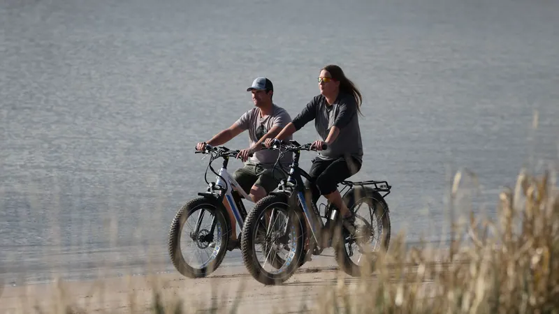 Couple riding fat-tire e-bikes along the shore