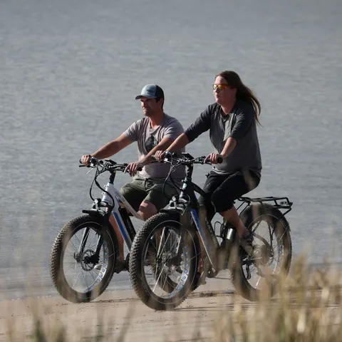 Couple riding fat-tire e-bikes along the shore