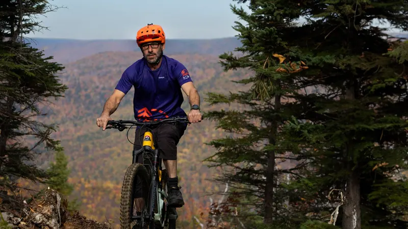 Mountain biker riding toward the camera above an autumn valley