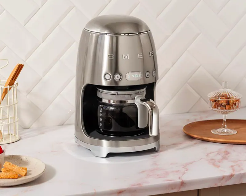 Stainless SMEG drip coffee maker on a marble kitchen counter