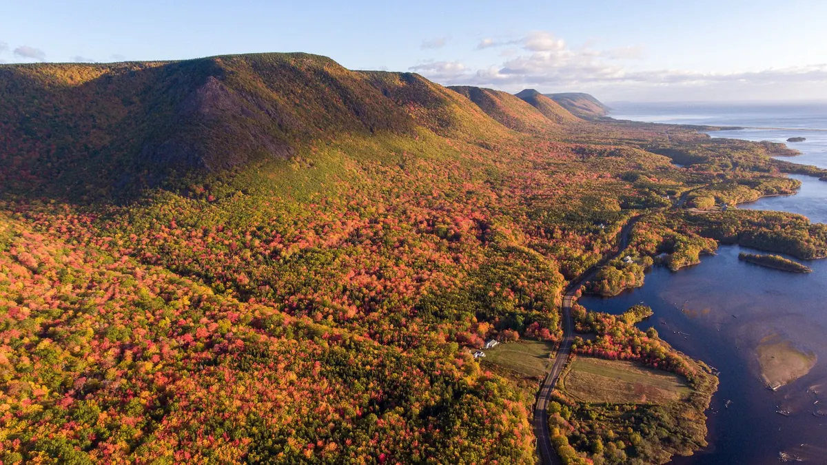 Aerial view of autumn-coloured highlands and a river valley along the Cabot Trail
