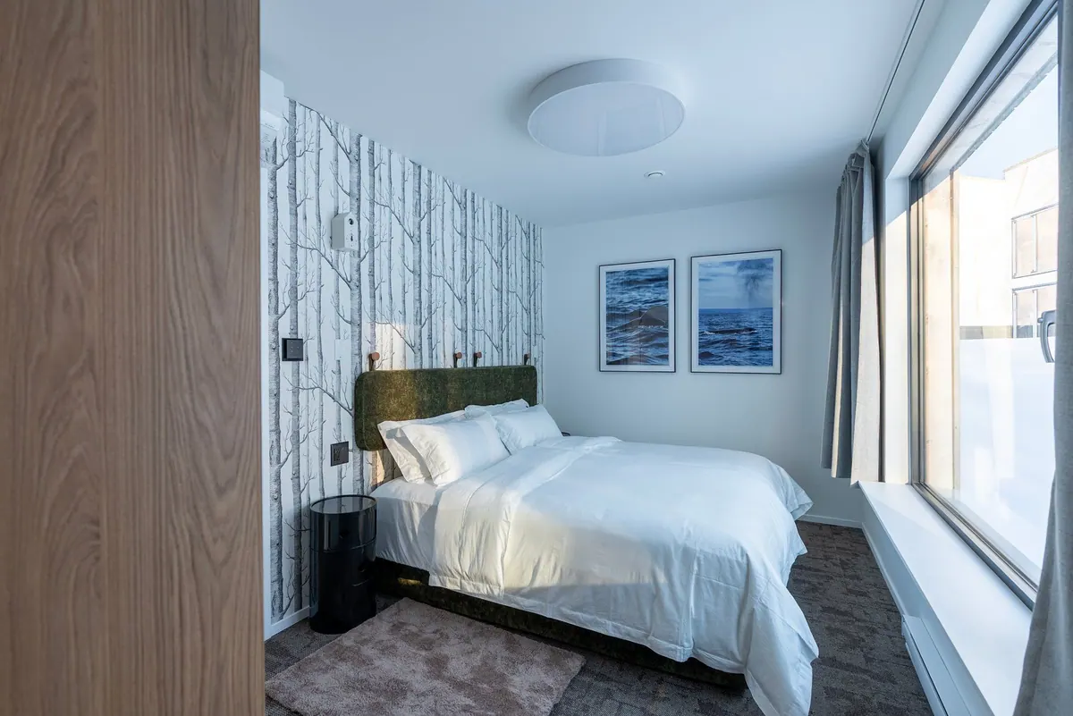 Bright bedroom with a king-size bed, birch-tree wallpaper and framed seascapes