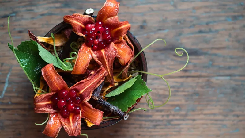 Plated dish garnished with red flower petals on a wooden table