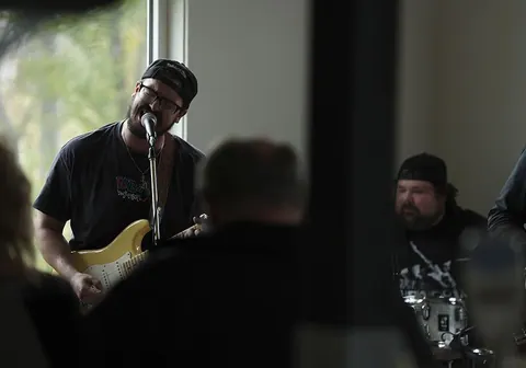 Smiling guitarist singing into a microphone during a live music session