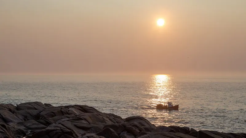Small boat on a sea glowing in a hazy sunset