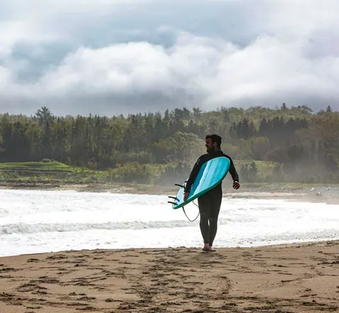 Surfer walking into the waves with a board
