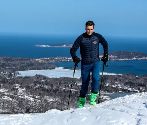 Winter hiker on a snowy ridge above the ocean