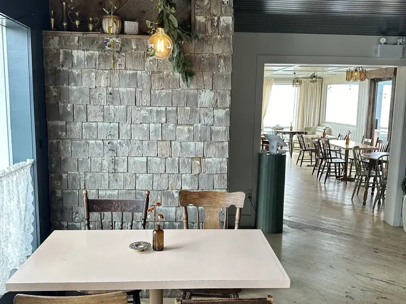 Dining room with stone wall, wooden tables and windows to the sea
