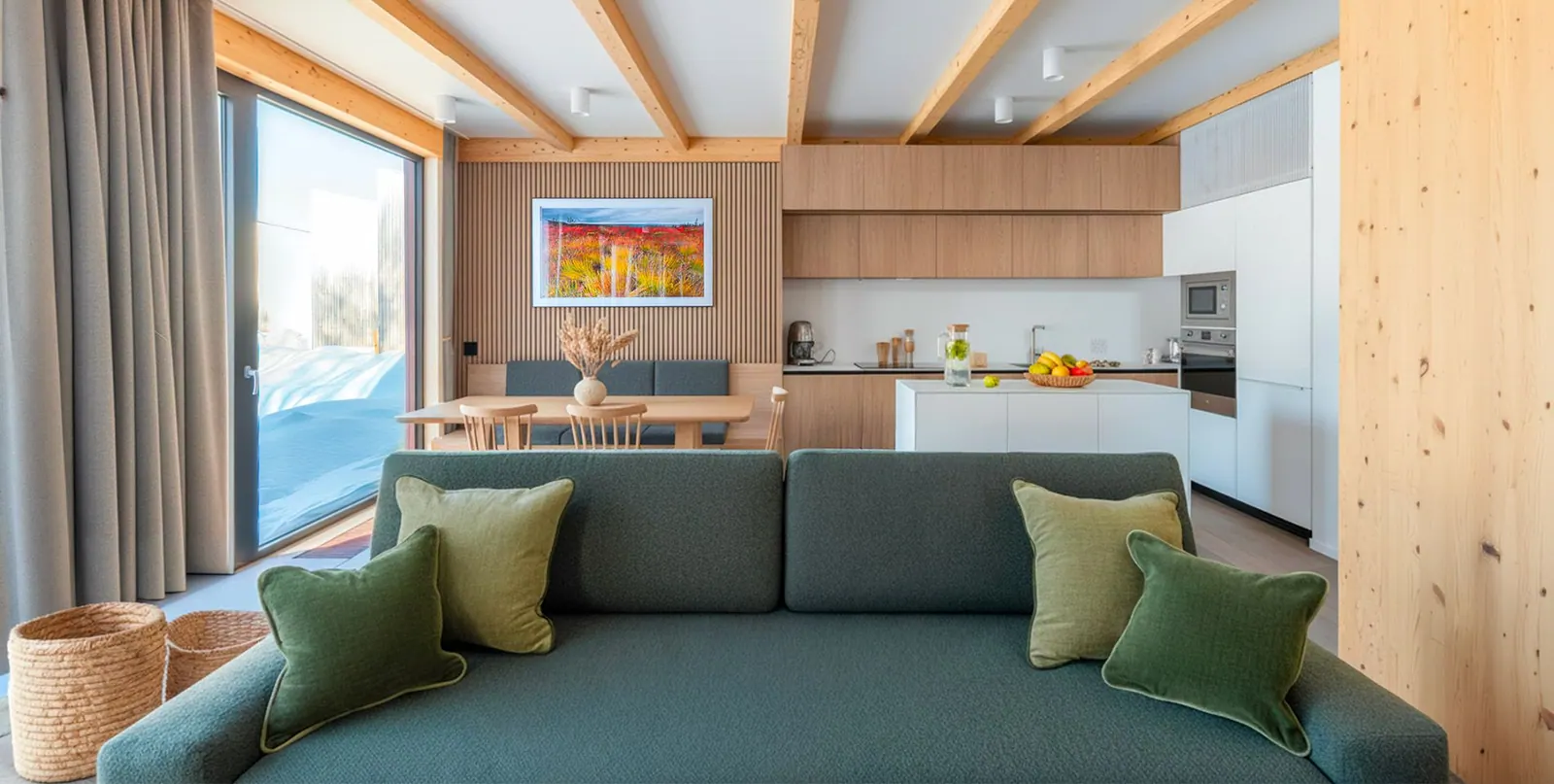 Chalet living room with a green sofa, open kitchen and timber walls