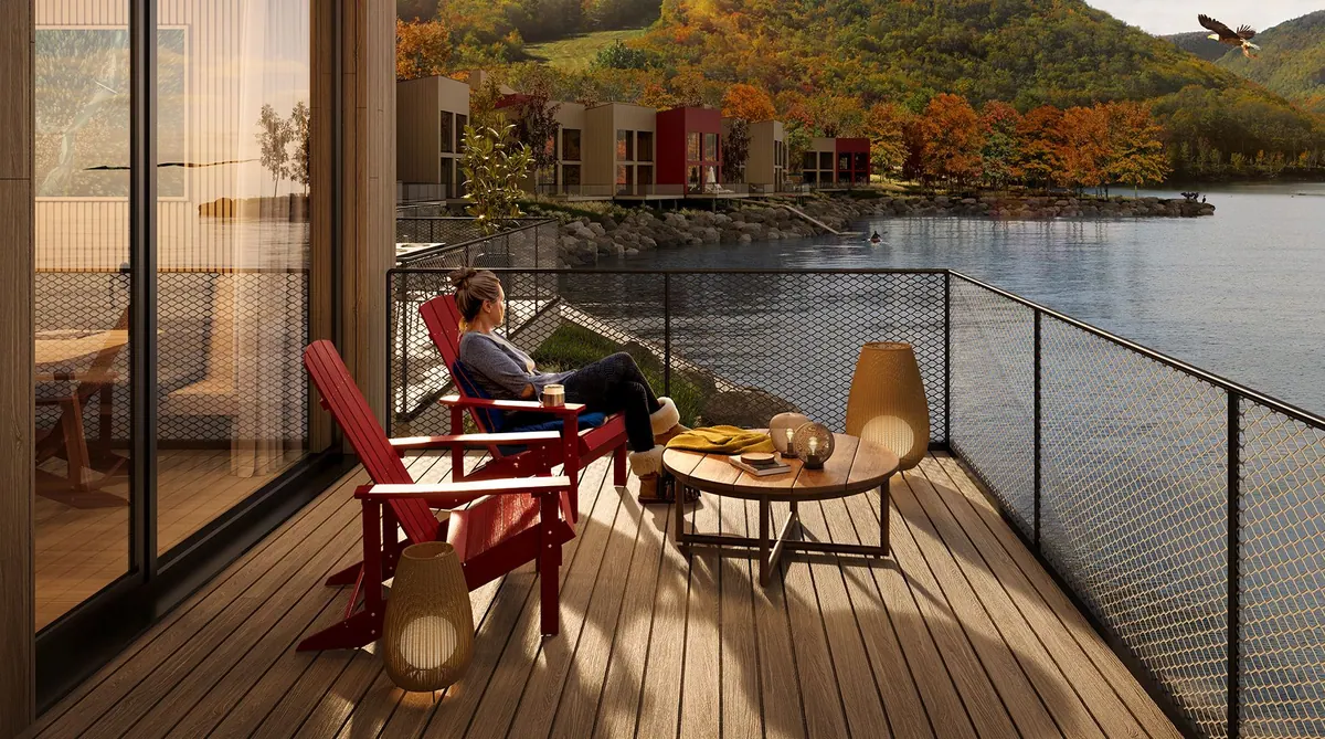 Guest relaxing on the chalet terrace with autumn hills across the water