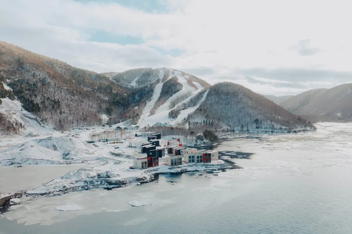 Aerial view of the Cormorant Rock chalets on the snowy shore below the Cape Smokey ski runs