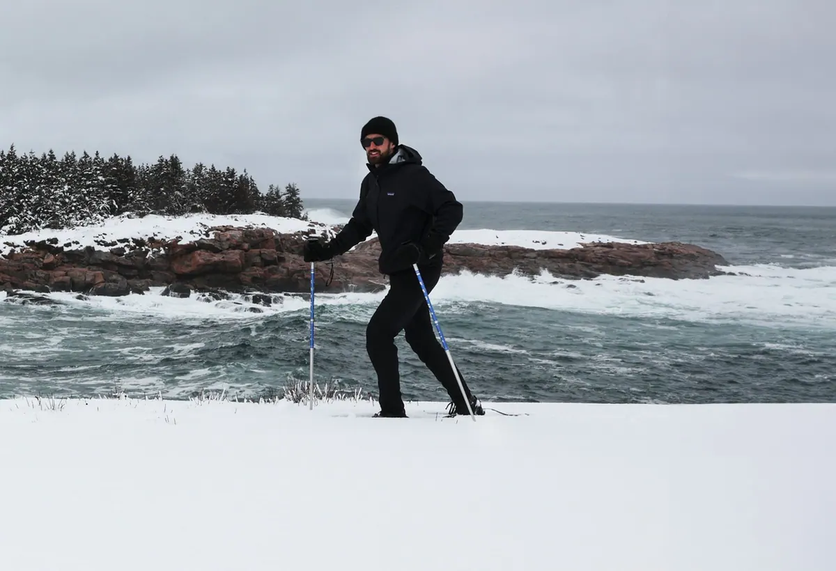 Snowshoer walking along a snowy, rocky shore