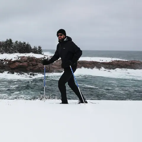 Snowshoer walking along a snowy, rocky shore