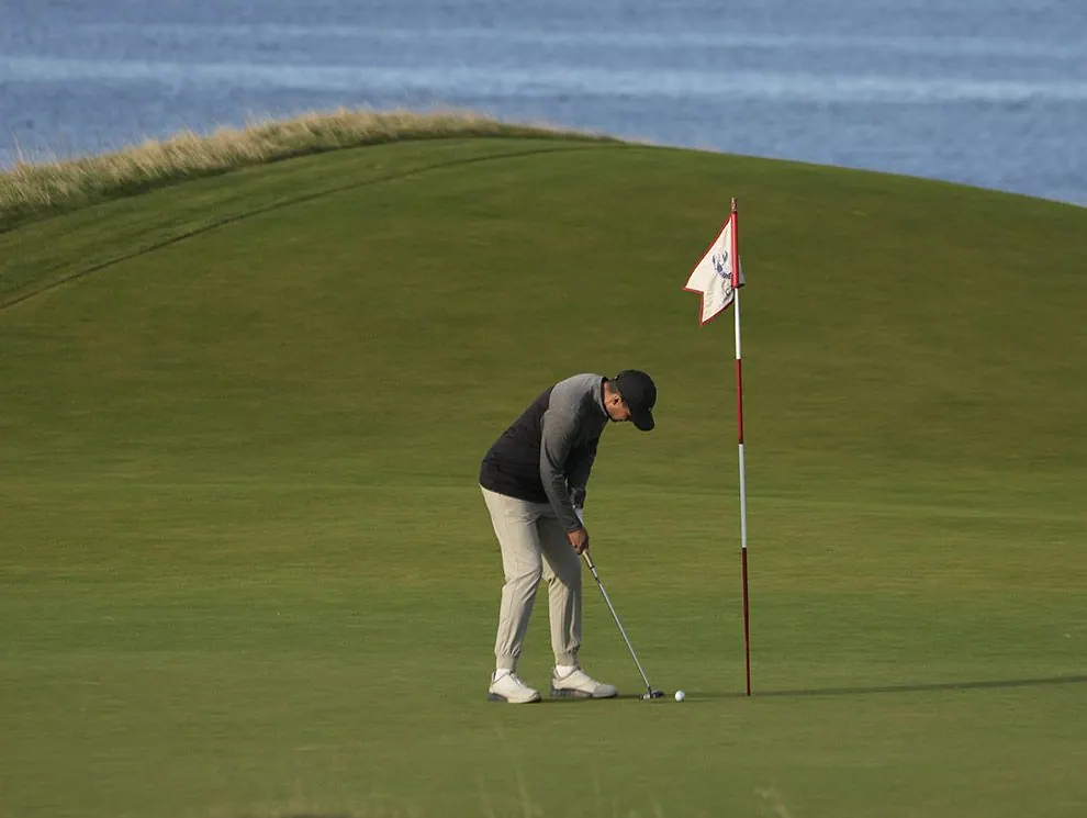 Golfer putting beside the flag on a green above the Atlantic