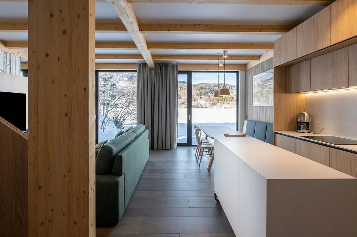 Open-plan chalet kitchen and living area with timber columns and a view of the bay
